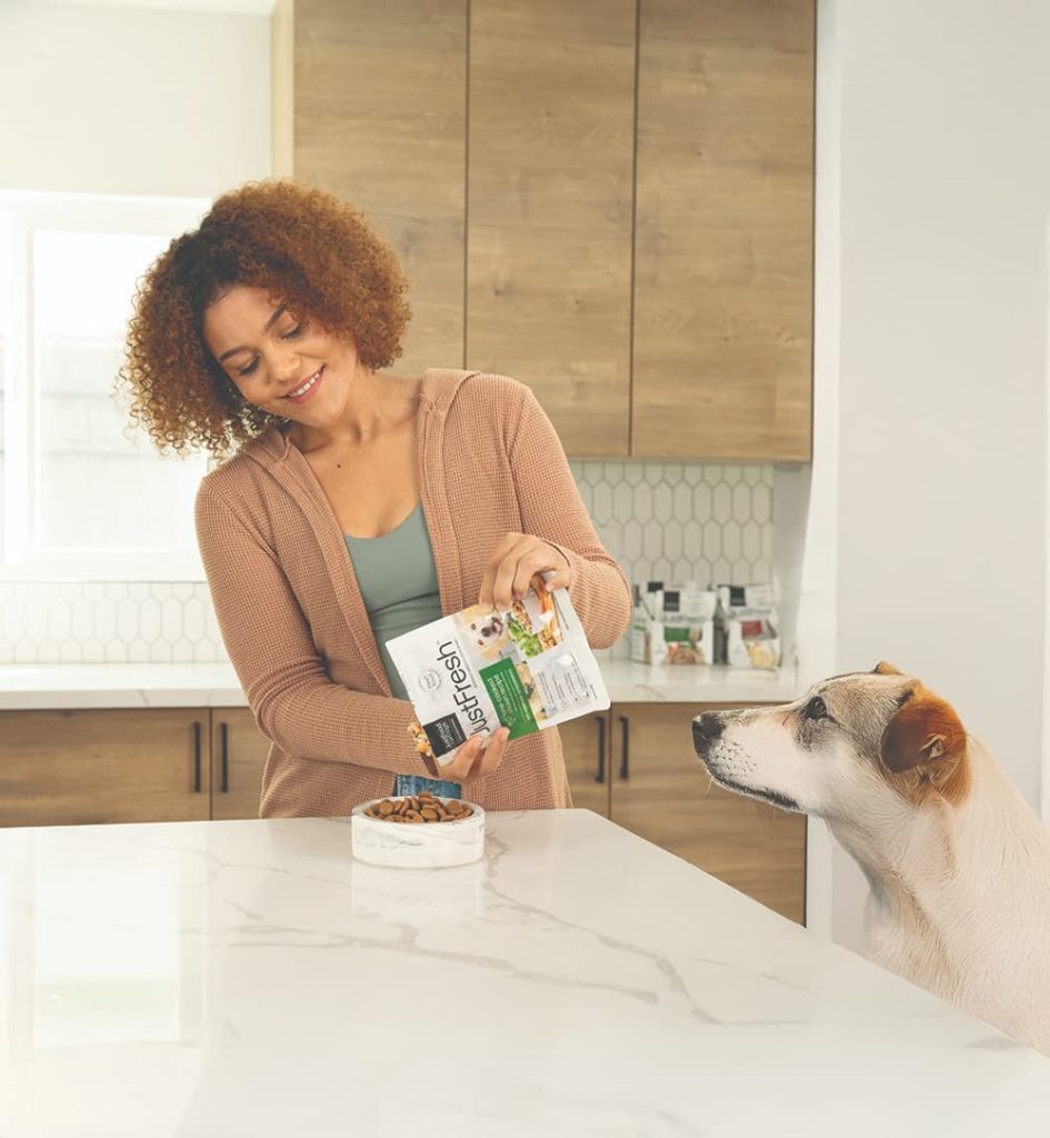 woman pouring fresh food into her dog's bowl